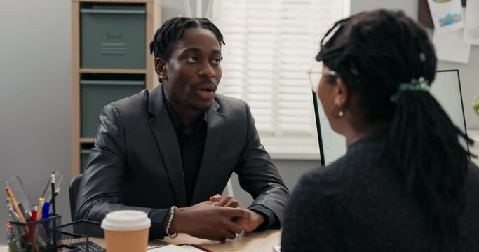 Smiling corporate executive conducts job interview with male candidate for office worker, accepts him into company, hires boy shakes hand congratulates welcomes says goodbye makes contract