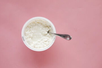 Fototapeta na wymiar cottage cheese in a bowl on pink background 
