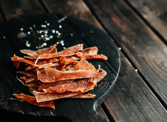 Dried chicken cut into strips on a wooden board with salt and pepper. High quality photo