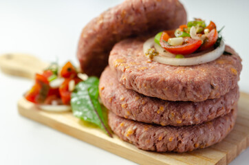 Raw beef burgers blended with caramelised red onion and tangy red Leicester cheese prepared for grilling