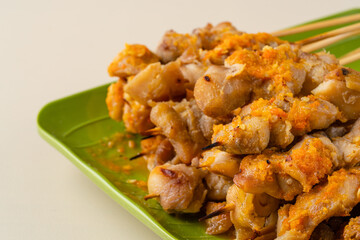 Sate taichan or Taichan satay with grilled chicken skin  is a variation of chicken satay grilled and served without peanut or ketchup served with chili sauce. Selective focus , blurry. 