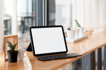 Mockup blank white screen portable tablet with keyboard on wooden counter table.