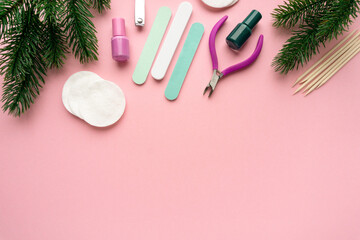 Obraz na płótnie Canvas Christmas flat lay of manicure accessories with fir branches on pink background, space for text