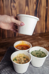 Close-up of soup in a glass. Takeaway food in disposable dishes. A paper cup with a hodgepodge, mushroom soup and croutons. The concept of fast food in a cafe.
