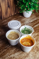 Close-up of soup in a glass. Takeaway food in disposable dishes. A paper cup with a hodgepodge, mushroom soup and croutons. The concept of fast food in a cafe.