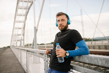 after training, the young athlete enjoys the view, refreshes himself with water and listens to music