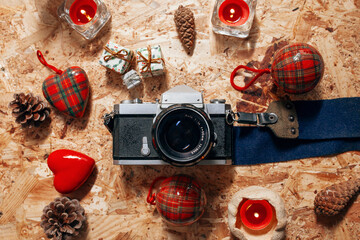 Still life with vintage camera, christmas decorations and pine cones over wooden background. Christmas, new year, winter concept. Flat lay, top view, copy space.