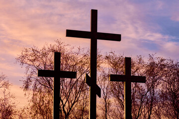 Three crosses in silhouette at sunset, dramatic sky