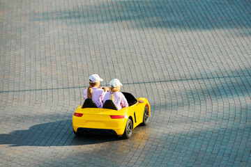 Two little girls driving toy car. Battery vehicle with remote control for children entertainment