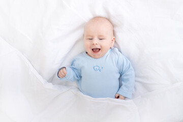 laughing baby boy on the bed under the blanket, healthy sleep baby