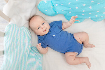 baby boy in a cot among pillows, concept of baby linen and textiles