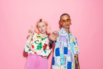 Young white couple in multicolored shirts gesturing at camera