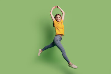 Portrait of cute charming ballerina lady jump dance wear yellow t-shirt jeans footwear on green...