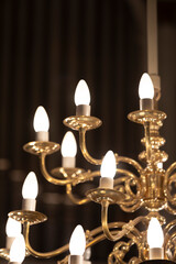 A gold plated chandelier with lights in front of a prospect of a pipe organ