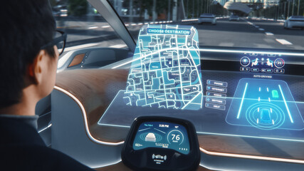Futuristic Concept: Stylish Businessman Setting Location on an Interactive Navigation App on an Augmented Reality Dashboard while Sitting in an Autonomous Self-Driving Zero-Emissions Electric Car.