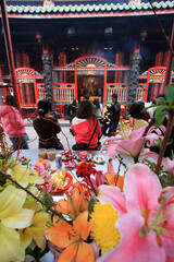 people praying at a temple in Taiwan with flowers in the foreground