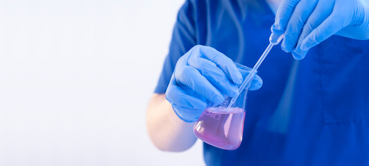 Close up chemical scientist developing a new drug by adding new element with disposable pipette. Wide banner with white copy space
