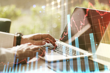 Abstract creative financial graph with hand typing on laptop on background, financial and trading concept. Multiexposure