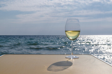Romantic glass of white wine, on the sea beach. Wine tasting and relaxation at the resort