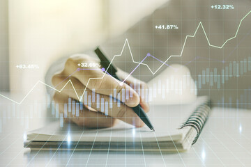Abstract creative financial graph with hand writing in notebook on background, forex and investment concept. Multiexposure