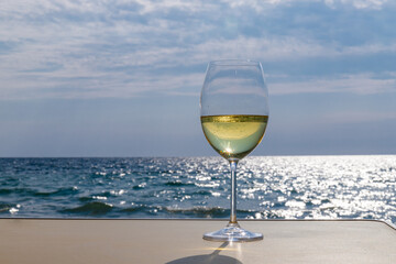 Romantic glass of white wine, on the sea beach. Wine tasting and relaxation at the resort
