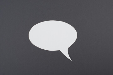 Empty speech bubble, white paper on a dark grey background, copy space for text, communication...