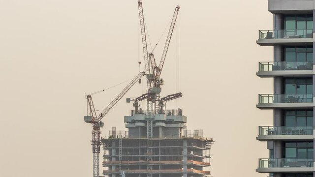 Skyscraper under construction with cranes and iron frame timelapse