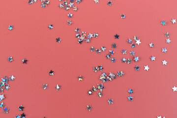 Glitter stars confetti on pink background in bright pastel colors. Festive Christmas background. Festive holiday pastel backdrop