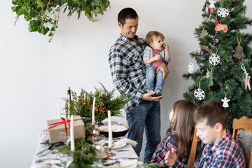 Family, dad with his son near the Christmas tree at home. Family breakfast at Christmas. The father shows his son a fir-tree. Christmas home