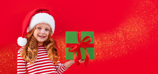Christmas banner child in a santa hat holding a gift on a red background with place for text	
