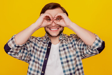 Photo of young cheerful excited man show fingers binoculars ok okey sign isolated over yellow color background