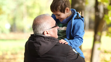 Grandfather and little grandson walking in the autumn park. soft selective focus
