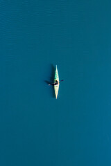 View from above, aerial view of a person paddling a canoe - kayak on the Cedrino Lake surrounded by the mountain range of Supramonte located northeast of the Gennargentu massif. Sardinia, Italy.