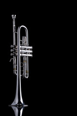 A piston silver plated C trumpet on a reflective surface on a black background. A brass instrument common in classical music.