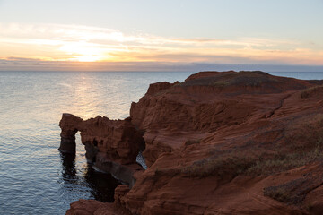 Rugged sunset landscape with red sandstone cliffs and arch over the ocean in Cap-aux-Meules, Magdalen Islands, Quebec, Canada