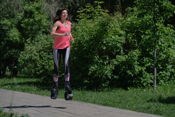 beautiful woman runs along the path in the park, legs in kangoo jumping shoes. women training Kangoo Jumping