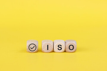 Wooden cube with the text ISO with check mark on  yellow background. ISO Quality Control Certification Concept