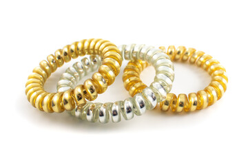 Close up photo of three metallic gold and silver plastic spiral hair ties