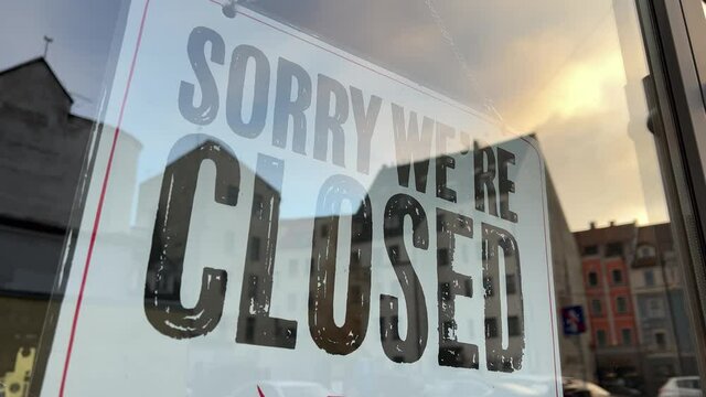 Sunset view over Sorry We're Closed sign at small street cafe's glass door