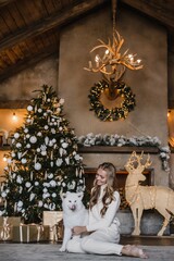 young beautiful woman model with long hair in a beige suit christmas tree christmas In brown wooden houses 