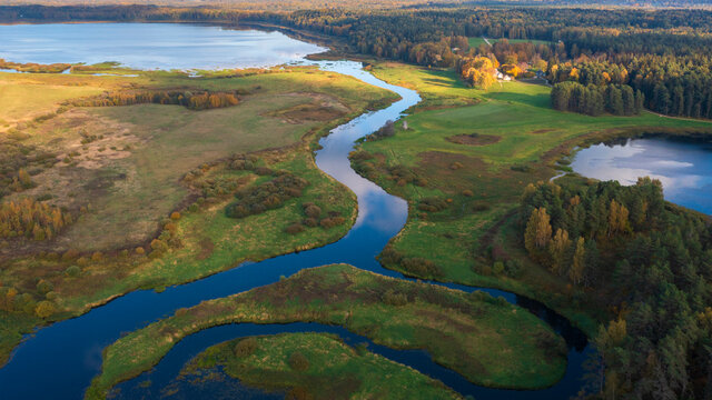 Beautiful early autumn landscape, field, river, lake and colorful forest. Pushkinskie Gory, Pskov Region Russia. top areal view from a drone