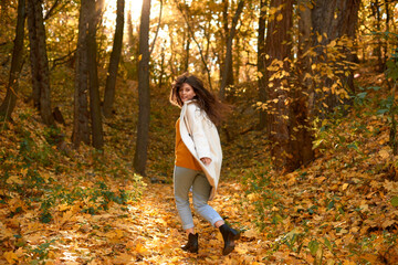 Fototapeta premium cheerful and happy girl runs away in yellow autumn forest. blurred photo