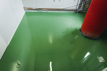 Fresh epoxy and waxed green floor newly applied in the industrial hall