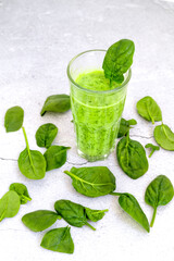 Top view of glasses filled with green smoothies on table with spinach leaves