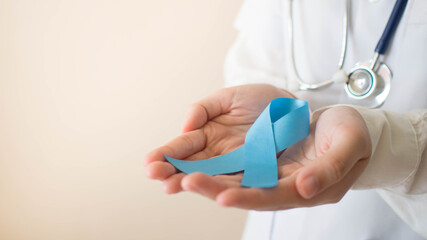 Men's health and Prostate cancer awareness campaign in November month. Close up of doctor hands holding light blue ribbon awareness. Symbol for support men who living w/ cancer. Copy space.