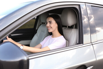 Fototapeta na wymiar Beautiful young woman driving her modern car