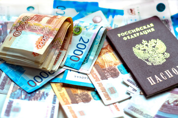 A Russian passport and a folded wad of money lying on Russian money. The concept of finance, investment, savings and cash.