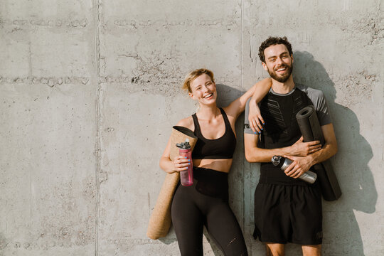 Young man and woman smiling while working out together on parking