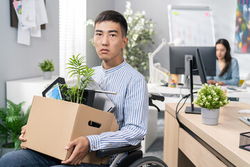 Disabled ambitious man in shirt with Asian Korean beauty sits in wheelchair at desk in the company...
