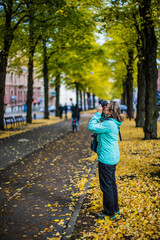 Fototapeta premium A woman doing photography in Gothenburg City, on a fall day, in Sweden